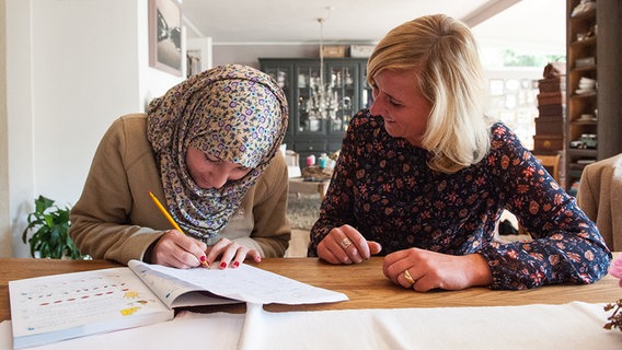 Eine geflüchtete Frau lernt Deutsch mit einer anderen Frau. © dpa - Bildfunk Foto: Philipp Schulze