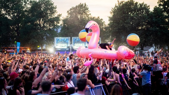 Zahlreiche Festivalbesucher feiern während des Konzerts der deutschen Band "SDP" auf dem Hurricane Festival mit einem überdimensionalen Flamingo. © Hauke-Christian Dittrich/dpa Foto: Hauke-Christian Dittrich