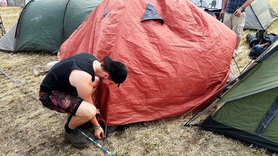 Ein Mann baut sein Zelt auf dem Gelände des Hurricane Festivals 2023 auf. © NDR Foto: Svenja Nanninga