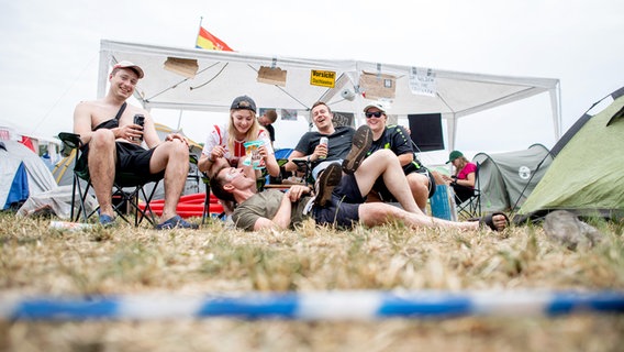 Vier Besucher des Hurricane Festivals sitzen vor ihrem Pavillon auf dem Zeltplatz. © dpa-Bildfunk Foto: Hauke-Christian Dittrich