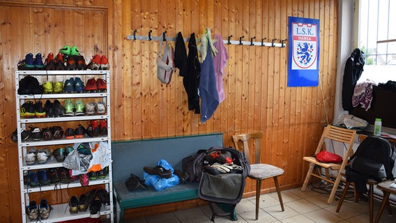 In einer Umkleidekabine im Vereinsheim des Lüneburger SK Hansa stehen Sportschuhe in einem Regal, an den Wandhaken hängen und auf den Bänken liegen Klamotten.  Foto: Lüneburger SK Hansa
