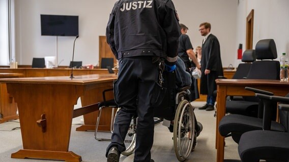 Der Angeklagte wird im Rollstuhl in den Saal des Landgerichts geschoben. © picture alliance/dpa Foto: Philipp Schulze