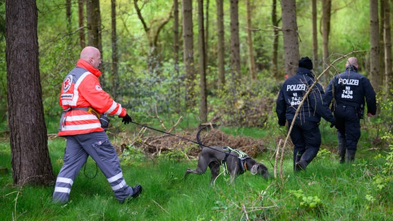 Einsatzkräfte des Roten Kreuzes sind mit einem Suchhund in einem Waldstück in Bremervörde im Einsatz, um einen vermissten Jungen Arian zu finden. © Daniel Reinhardt / dpa Foto: Daniel Reinhardt