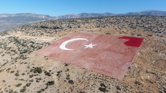 Eine riesige türkische Flagge ist auf dem Boden in der Provinz Mersin zu sehen. © picture alliance / AA | Ahmet Guler Foto: Ahmet Guler