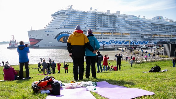 Schaulustige stehen am Ems-Sperrwerk Gandersum und beobachten die Überführung des Kreuzfahrtschiffes «AIDAnova» auf der Ems. © dpa-Bildfunk Foto: Mohssen Assanimoghaddam
