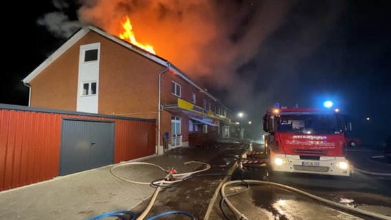 Feuerwehrleute löschen auf Borkum ein Haus, aus dessen Dach Flammen schlagen. © NonstopNews 