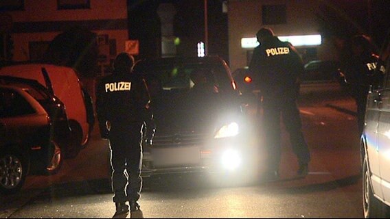 Zwei Polizeibeamte kontrollieren einen Wagen bei nacht. © NDR 