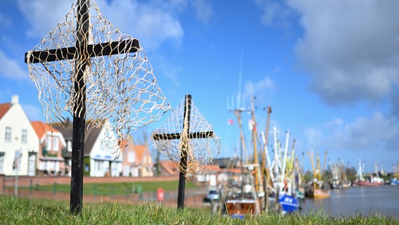 Schwarze Kreuze mit Netzen stehen als Stiller Protest der Fischer am Hafen von Greetsiel. © dpa Foto: Lars Klemmer