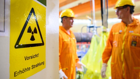 Zwei Mitarbeiter stehen im Kernkraftwerk Unterweser neben einem Schild mit der Aufschrift "Vorsicht! Erhöhte Strahlung". © picture alliance Foto: Mohssen Assanimoghaddam