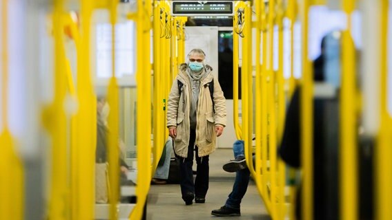 Eine Frau steigt mit einer OP-Maske in eine Bahn. © picture alliance/dpa Foto: Christoph Soeder