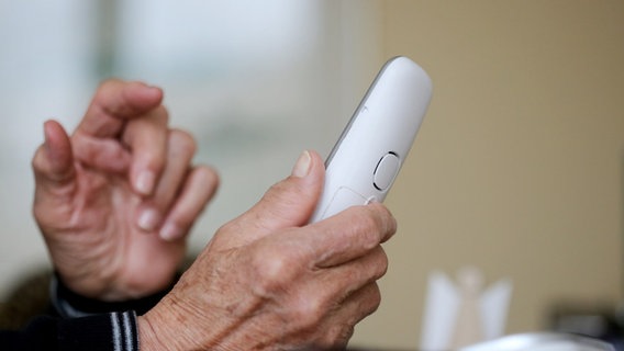 Ein Senior hält einen Telefonhörer in der Hand. © dpa-Bildfunk Foto: Roland Weihrauch