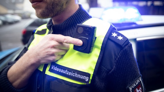 Ein Polizist startet mit einem Finger eine Bodycam. © picture alliance/dpa Foto: Friso Gentsch