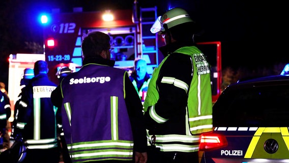 Ein Mitarbeiter der Seelsorge neben einem Feuerwehrmann an einer Unfallstelle. © Nord-West-Media TV Foto: Nord-West-Media TV