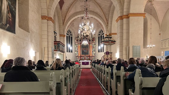 Menschen sitzen bei einer Gedenkfeier in einer Kirche in Bramsche. © kirche.media/dpa 