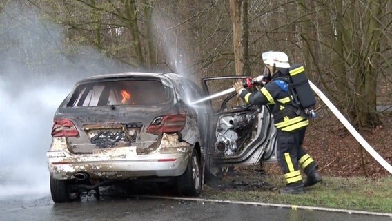 Einsatzkräfte der Feuerwehr löschen einen Pkw nach einem Unfall bei Gehrde. © NWM TV 