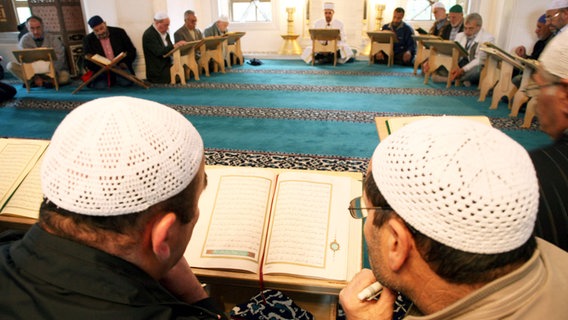 Zwei Muslime lesen am "Tag der offenen Moschee" in der Sehitlik-Moschee am Columbiadamm in Berlin in einem Koran. © dpa Foto: Rainer Jensen