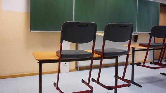 Kreidetafel einer allgemeinbildenden Schule. Im Vordergrund sind Tische und Stühle zu sehen. © picture alliance / Fotostand 