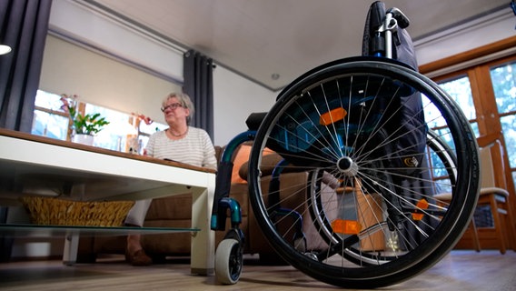 Ein Rollstuhl steht in einem Wohnzimmer. © NDR 