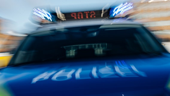 Ein mit Bewegungsunschärfe fotografiertes Polizeiauto mit Blaulicht und Stop in der Anzeigetafel. © NDR Foto: Julius Matuschik