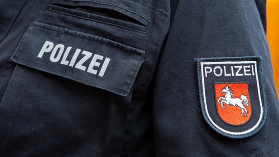 Der Schriftzug "Polizei" und das Niedersachsen-Pferd auf einer Polizeiuniform. © dpa Foto: Fotostand / Gelhot