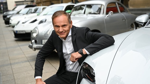Oliver Blume, Vorstandsvorsitzender der Volkswagen AG und der Porsche AG, kniet beim Börsengang der Porsche AG vor der Frankfurter Börse an einem Porsche. © picture alliance/dpa Foto: Arne Dedert