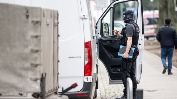 Ein Polizist steht an einem Transporter vor der Wohnung der ehemaligen RAF-Terroristin Daniela Klette. © picture alliance/dpa | Fabian Sommer Foto: Fabian Sommer