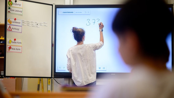 Eine Lehrerin schreibt eine Mathematikaufgabe auf eine digitale Schultafel im Klassenraum einer 4. Klasse einer Grundschule in der Region Hannover. © picture alliance/dpa | Julian Stratenschulte Foto: Julian Stratenschulte