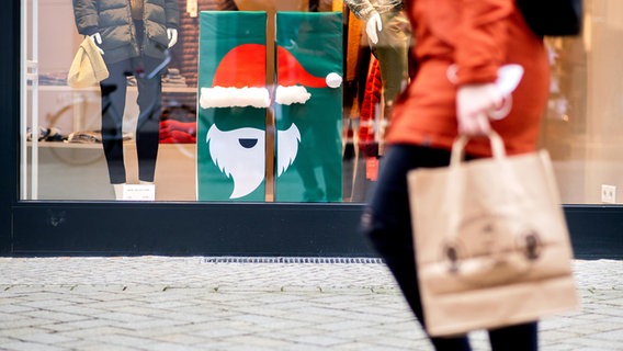 Eine Frau geht in der Innenstadt an einem Geschäft mit Weihnachtsdekoration im Schaufenster vorbei. © picture alliance/dpa | Hauke-Christian Dittrich Foto: Hauke-Christian Dittrich