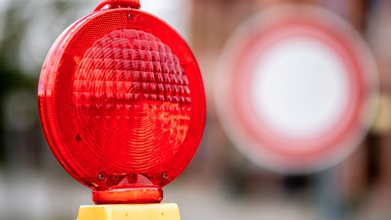 Eine rote Warnleuchte hängt an einer Baustelle vor einem Verkehrsschild, das auf die verbotene Durchfahrt für Fahrzeuge aller Art hinweist. © picture alliance/Hauke-Christian Dittrich Foto: Hauke-Christian Dittrich