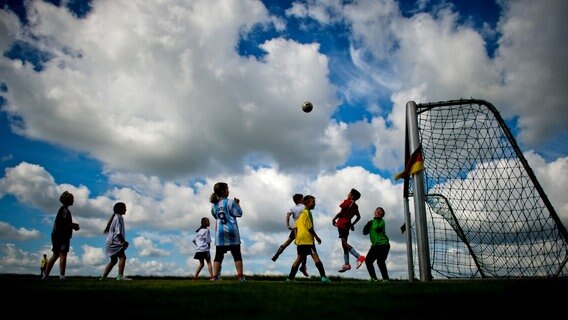 Mehrere Kinder spielen auf einem Sportplatz mit einem Ball © dpa Foto: Julian Stratenschulte