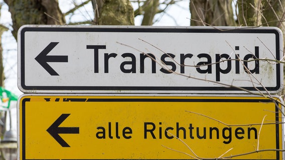 Auf Schildern steht "Transrapid" und "alle Richtungen". © dpa-Bildfunk Foto: Friso Gentsch
