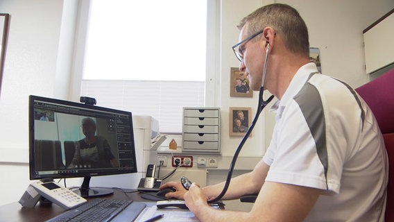 Ein Arzt sitzt vor seinem PC und behandelt eine Patientin bei einer Videosprechstunde. © Thees Jagels Foto: Thees Jagels