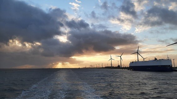 Die Sonne geht am Himmel hinter der Einfahrt zum Borkumanleger in Emden unter. © NDR Foto: Sarah Hartmann