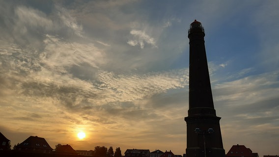 Die Sonne geht hinter dem Leuchtturm von Borkum auf. © NDR Foto: Heike Scheibe