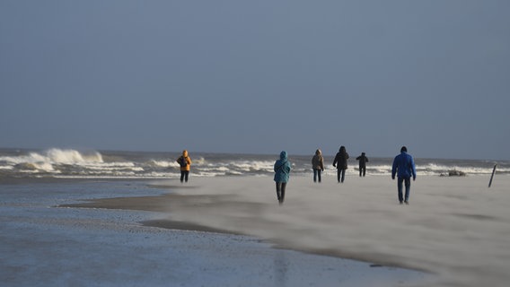 Spaziergänger bei Sturm am Strand von Langeoog © NDR Foto: Boris Weigl