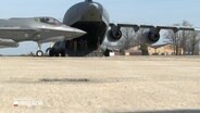 Auf einem militärischem Flugplatz stehen ein Transporter und ein Kampfjet. © NDR 