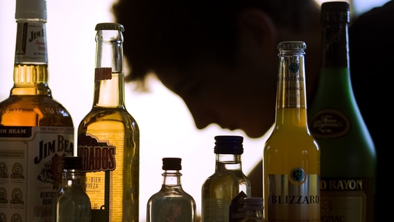 Ein Jugendlicher sitzt hinter Flaschen mit Alkohol. © picture alliance / dpa Foto: Jens Büttner
