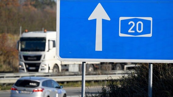 Ein Schild weist die A20 aus, auf der ein Auto fährt. © picture alliance/dpa | Carsten Rehder Foto: Carsten Rehder