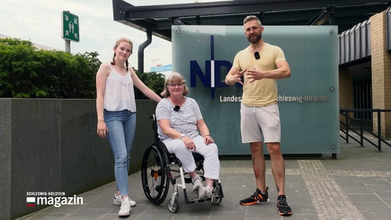 NDR Reporter Philipp Jeß posiert mit einer jungen Frau und einer Dame im Rollstuhl für die Kamera. © NDR 