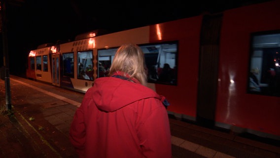Eine Frau steht auf dem Gleis und schaut dem abfahrenden Zug hinterher. © NDR Foto: NDR