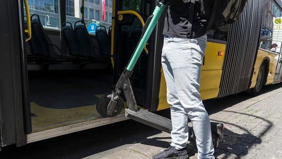 Eine Person versucht mit einem E-Tretroller in einen Bus einzusteigen © picture alliance Foto: Robert Guenther