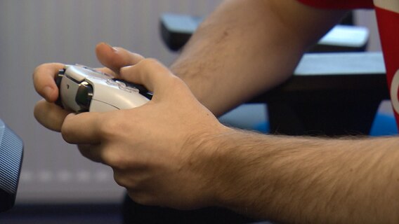 Ein eSport-Spieler hält ein Gamepad in der Hand. © NDR 