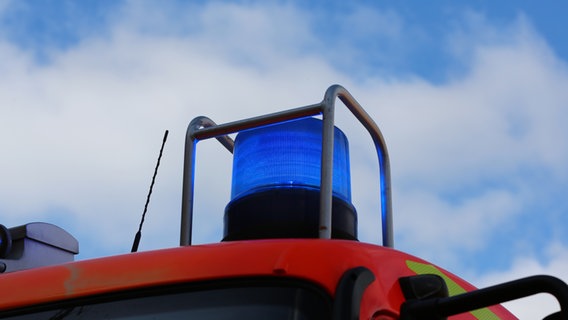 Ein Blaulicht leuchtet an einem Einsatzfahrzeug der Feuerwehr vor leicht bewölktem Himmel. © NDR Foto: Pavel Stoyan