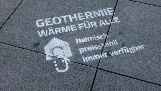 Auf dem Boden einer Straße steht mit weißer Farbe geschrieben: "Geothermie für alle. Heimisch, preisstabil, immer verfügbar" © IMAGO/Sascha Steinach Foto: IMAGO/Sascha Steinach