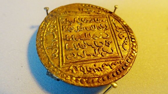 Eine antike Münze mit arabischer Schrift aus Gold. © NDR Foto: Peer-Axel Kroeske