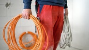 Ein junger Handwerker hält zusammengerollte Kabel in der Hand. © dpa-Bildfunk Foto: Britta Pedersen