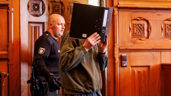 Angeklagter versteckt sich hinter Ordner bei Prozess gegen angeblichen Heilpraktiker in Flensburg © dpa-Bildfunk Foto: Axel Heimken/dpa