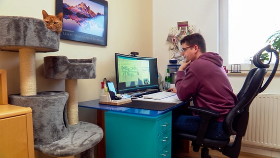 Ein Mann sitzt in seinem häuslichen Arbeitszimmer am Schreibtisch. © NDR 