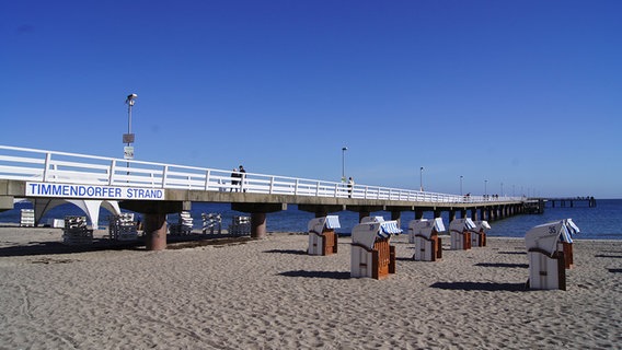 Blick auf die Seebrücke in Timmendorfer Strand . Am Strand stehen mehrere Strandkörbe. © NDR Foto: Hauke von Hallern