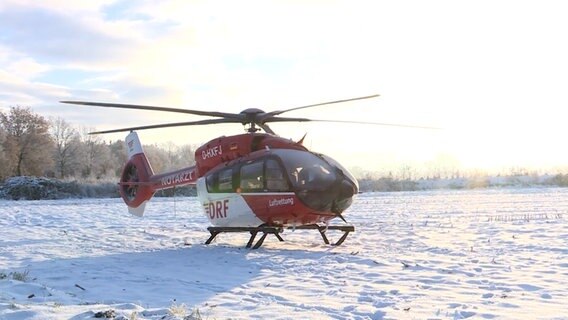 Ein vereister Hubschrauber der DRF Luftrettung steht auf einem Feld. © westkuesten-news.de Foto: Florian Sprenger